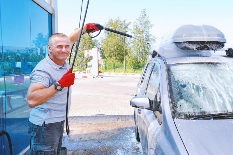 Nöjd man rengör sin bil med skumtvätt.